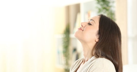 woman taking deep breathe inside home