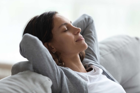 woman relaxing at home with hands behind head